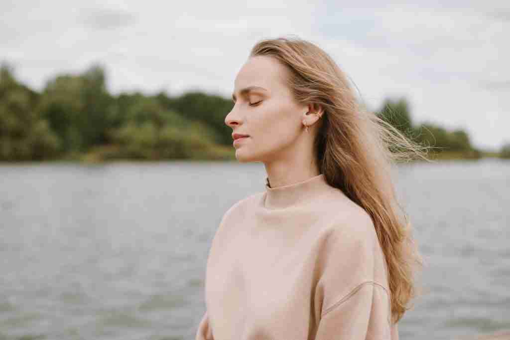 Close up of young woman meditating outdoors. Self-analysis and soul-searching concept.