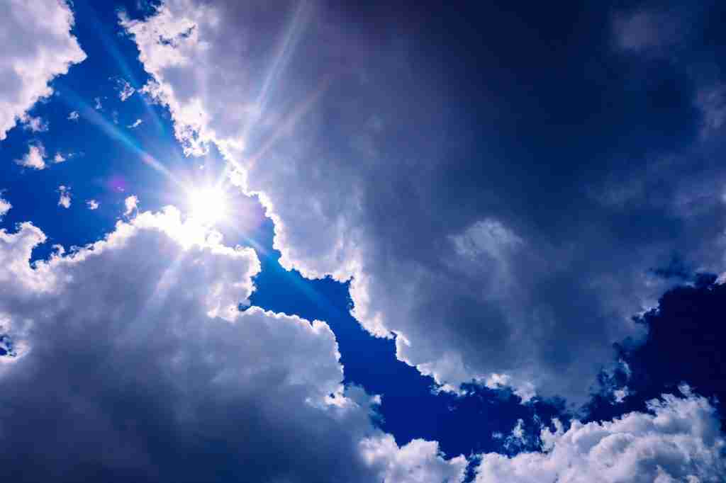 The sun rises between divine-inspired bluish storm clouds.